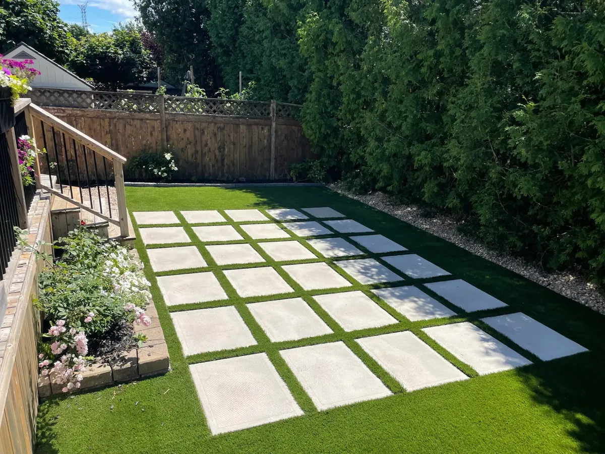 Premium Rymar Everblade 80 artificial turf at CA$14 per square foot installed with concrete stepping stones and planted borders
