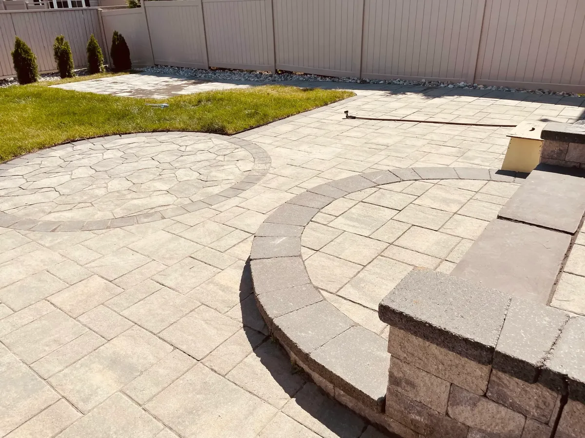 Professionals installing pavers beside Rymar Everblade 80 artificial turf at CA$14 per square foot installed around an outdoor kitchen